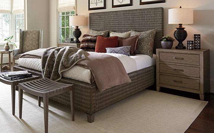 Cypress Point bedroom features a brown v-weave woven rattan bed, two nightstands, and two wood ottomans.