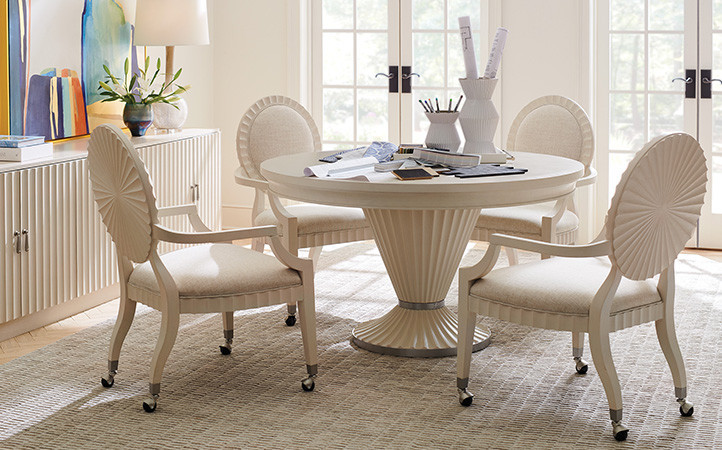 Ivory table with four ivory chairs with caster wheels along side a long media console.
