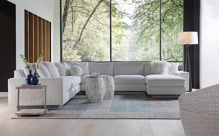 Artistica Upholstery scene featuring a white sectional, one natural color side table, and two stone round accent tables.