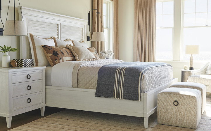 Ocean Breeze bedroom features a white king bed, two nightstands, and two small upholstered square ottomans.