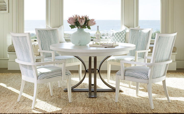 Ocean Breeze dining room features a white round dining table with dark base and four multi-color upholstered dining  chairs.